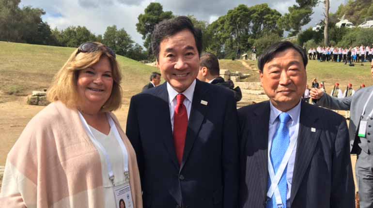 Sydkoreas premiärminister Lee Nak-Yeon, svenska Gunilla Lindberg, som är ordförande i IOK:s koordinationskommitté för OS i PyeongChang och Lee Hee-Beom som är ordförande i spelens organisationskommitté framför gräsängar med lite folk i bakgrunden.