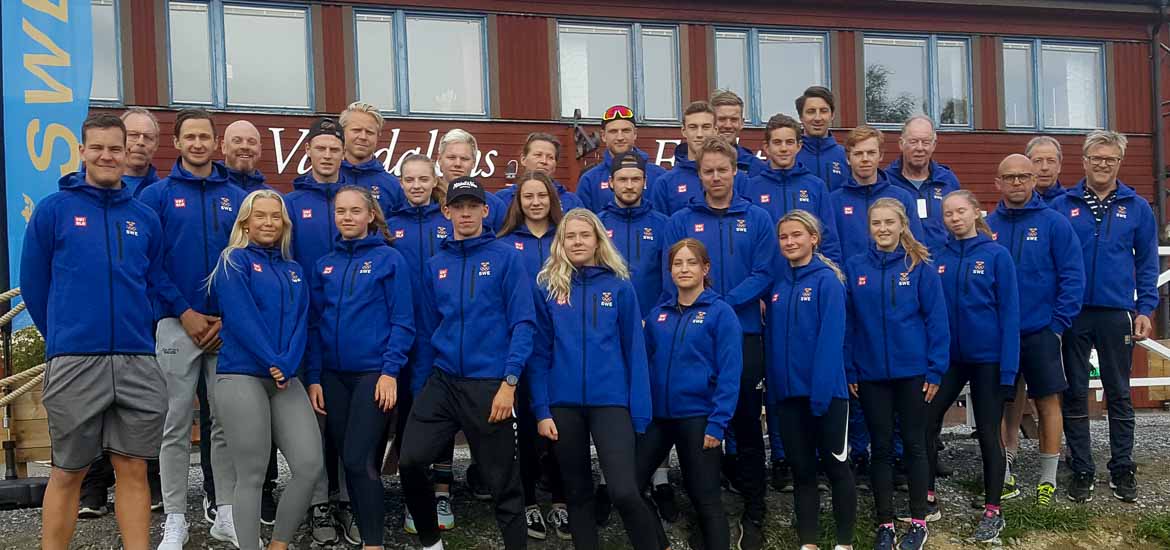 Gruppbild på aktiva och ledare framför Vålådalens fjällstations röda stuga.