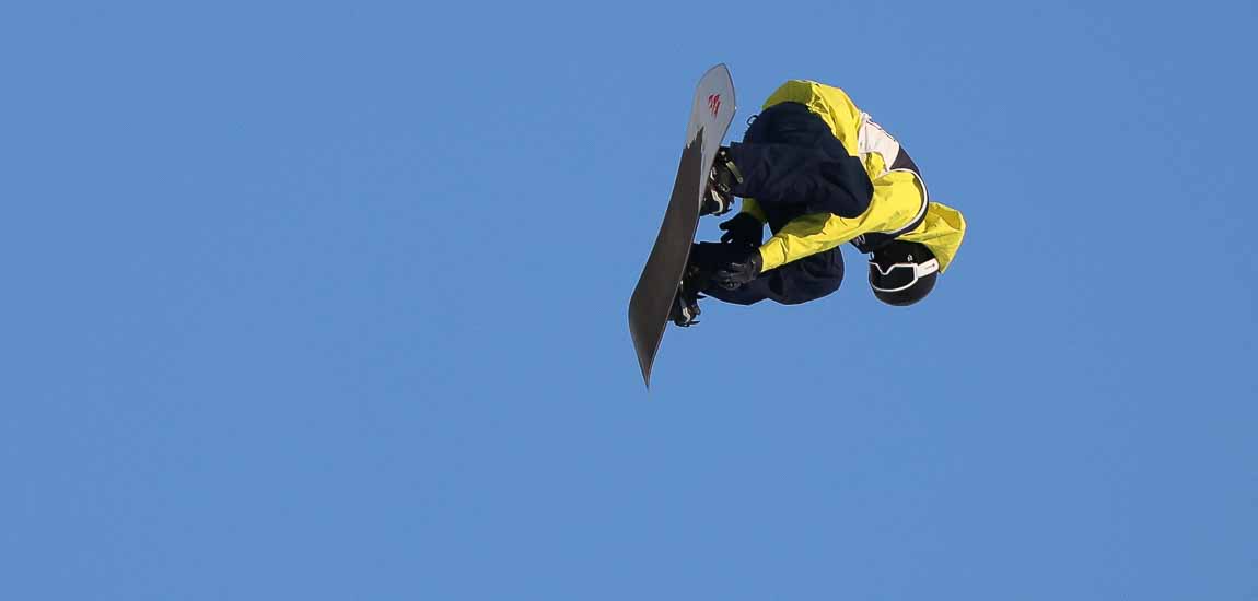 En snowboardåkare med gul jacka i luften.