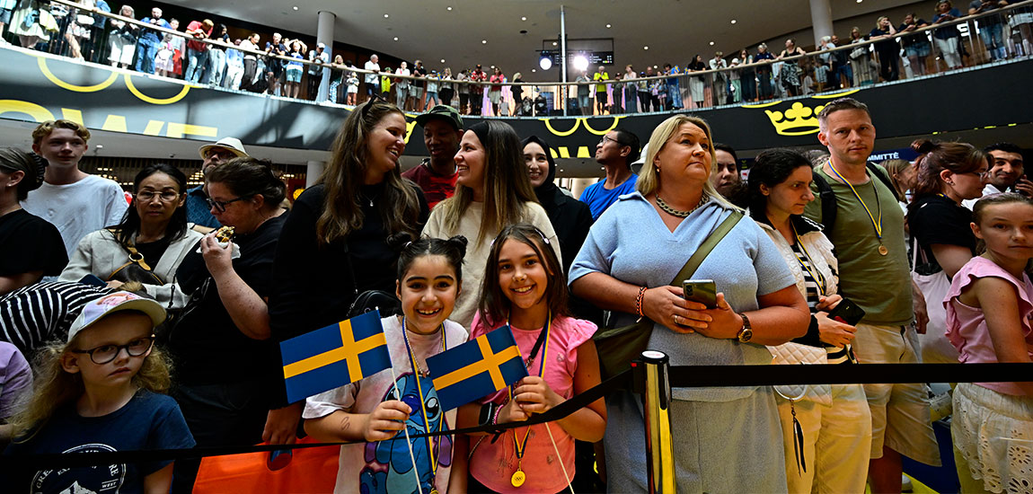 Människor i gula och blå kläder med svenska flaggor.
