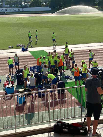 En samling med gul och blåklädda fotbollsspelare gör sig redo vid sidan av en fotbollsplan.