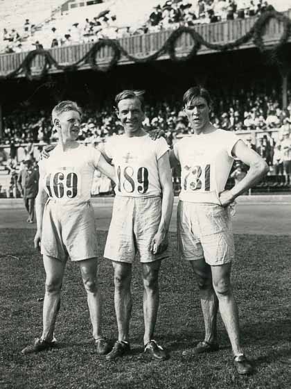 Tre herrar i vita shorts och tröja ler mot kameran. 