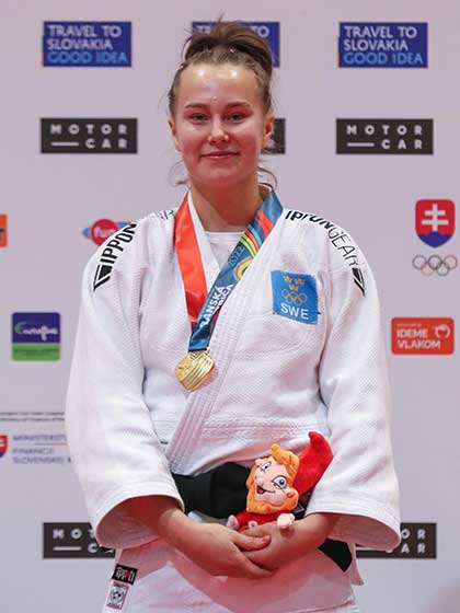 En flicka i judodräkt med guldmedalj runt halsen.