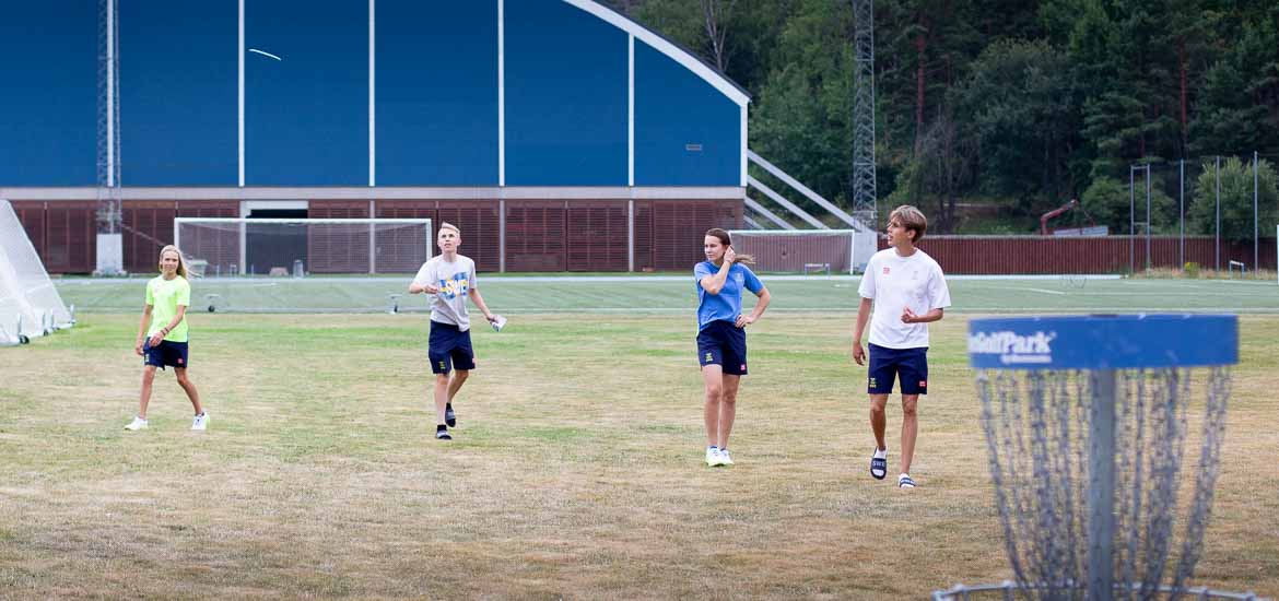 Fyra ungdomar spelar frisbeegolf tillsammans.