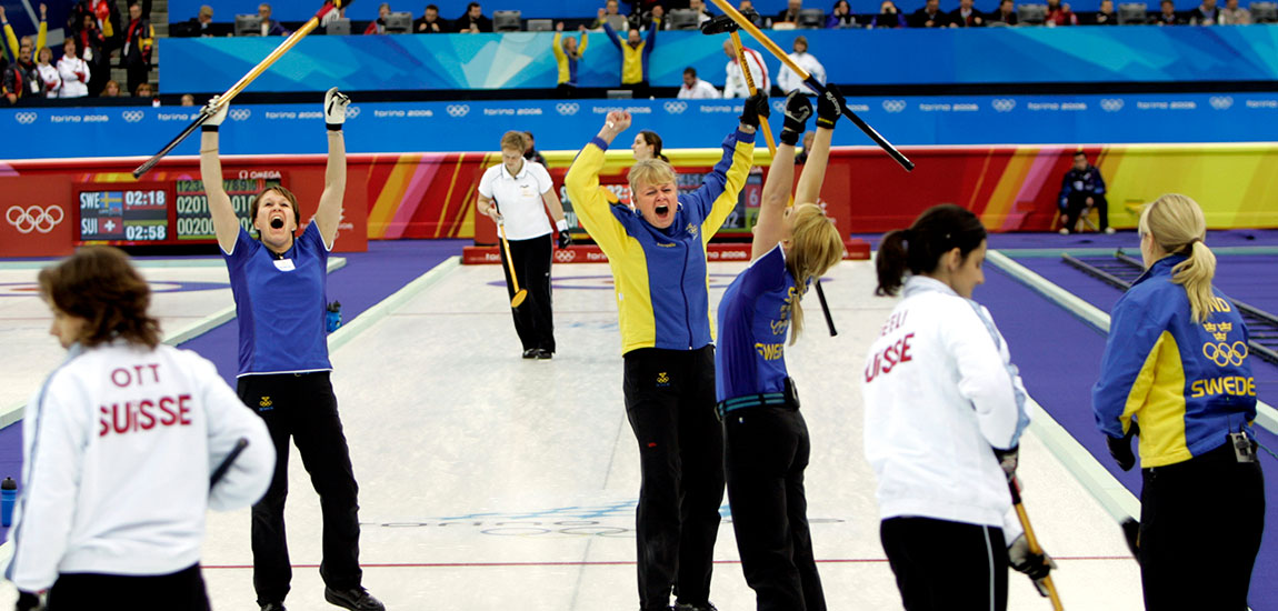 Jublande svenska curlingspelare som sträcker kvastarna i luften.