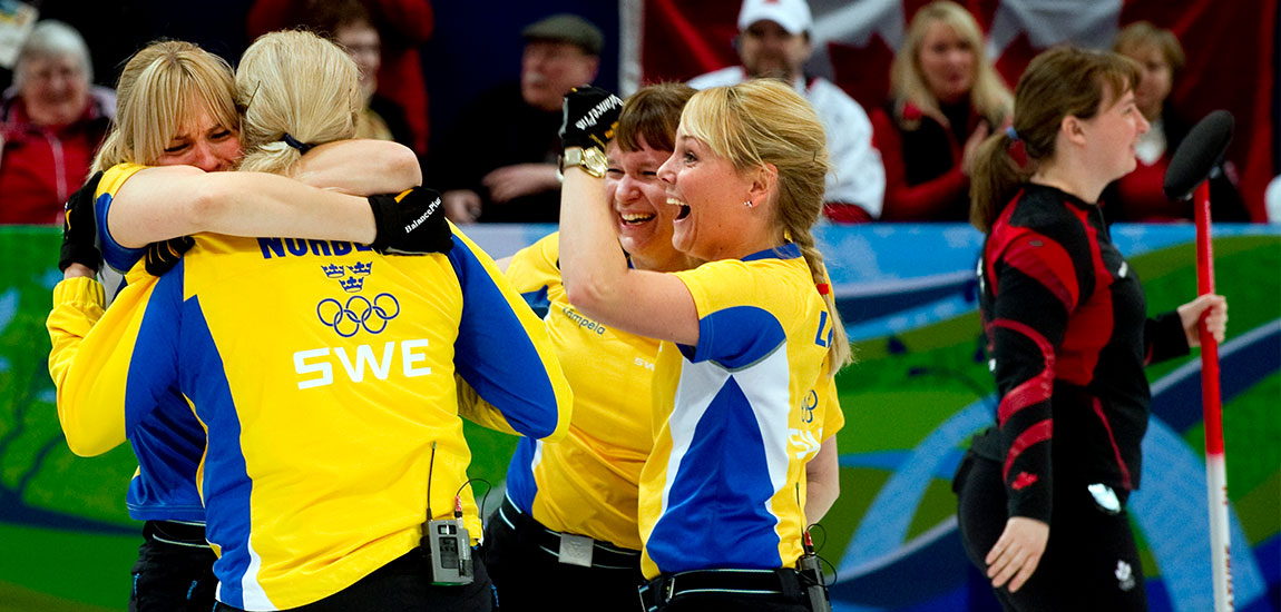Jublande svenska curlingspelare som kramar varandra.