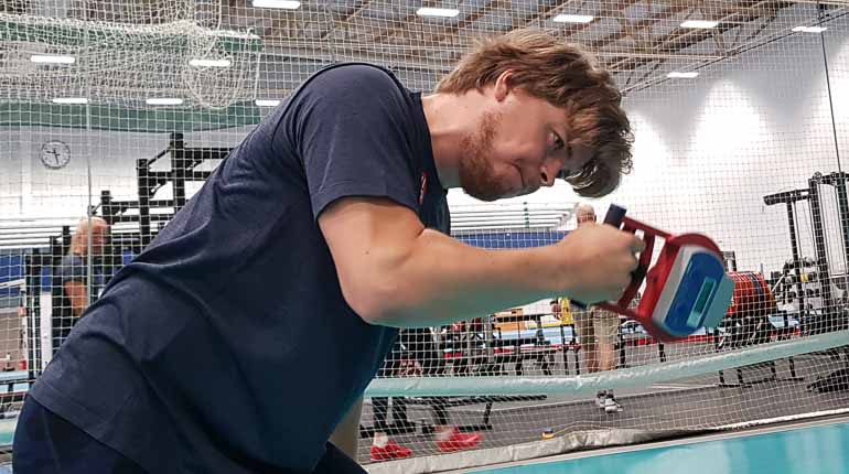 Fokuserat ansikte som grimarserar av ansträngning och en hand som griper i en mätare som mäter gripstyrkan.